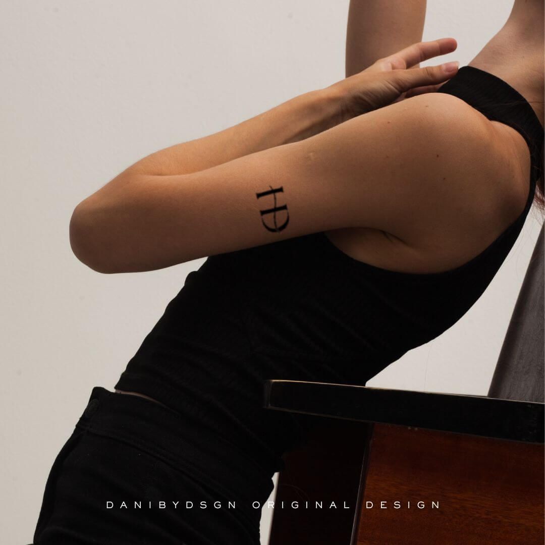 Sleek 'HD' monogram tattoo design on the upper arm, embodying Danibydsgn's signature initial monogram and custom logo design. This image marries the personal branding essence with body art, perfect for clients seeking business logo designs that can also translate into unique tattoos art and name monogram statements for individual expression. Our initial monograms are also versatile perfect for wall art, weddings, special event marketing, clothing branding and of course tattoo art and body art.