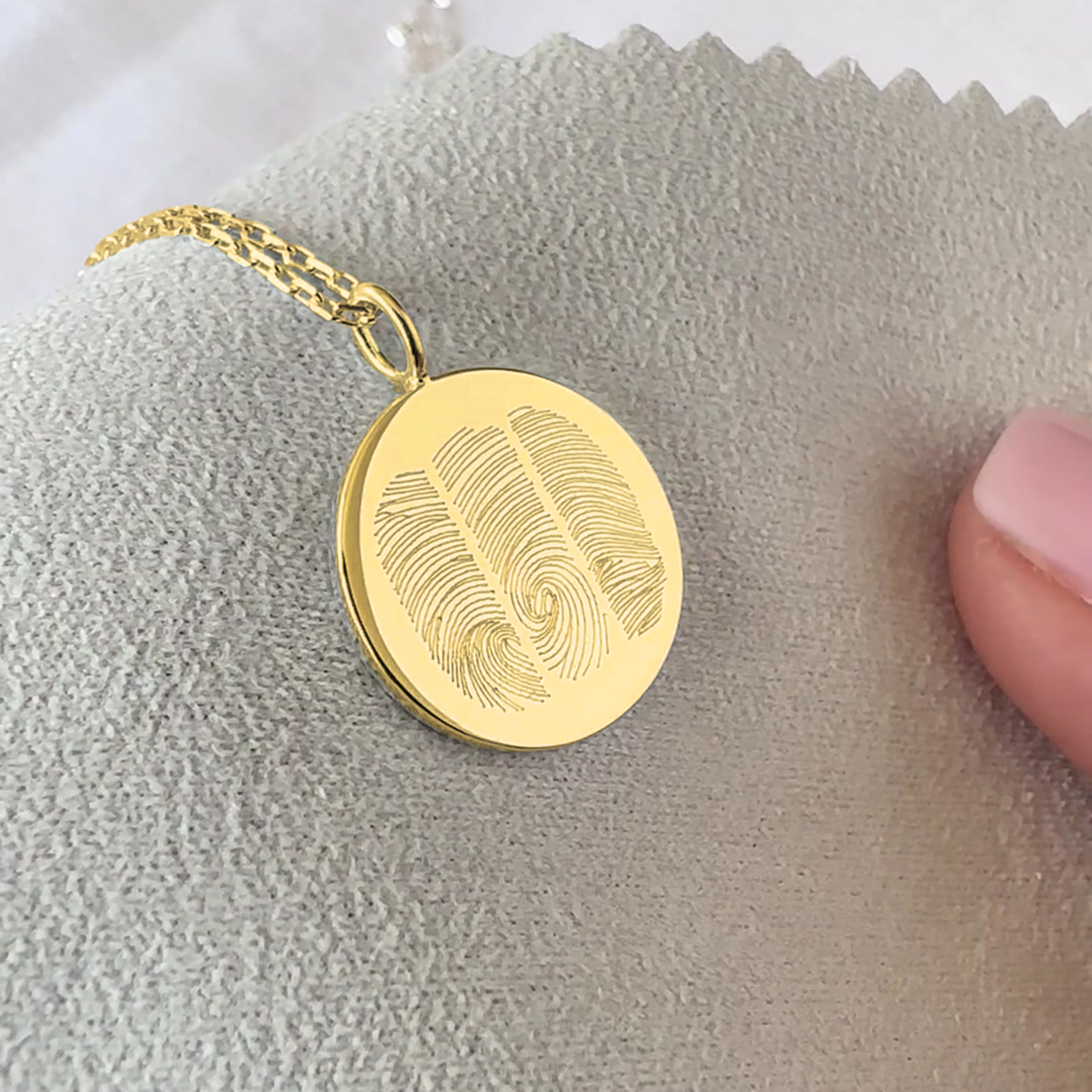 18k Gold Vermeil luxury coin pendant necklace with 3 fingerprints engraved on the pendant and pendant is on a chain on a light grey velvet cloth.