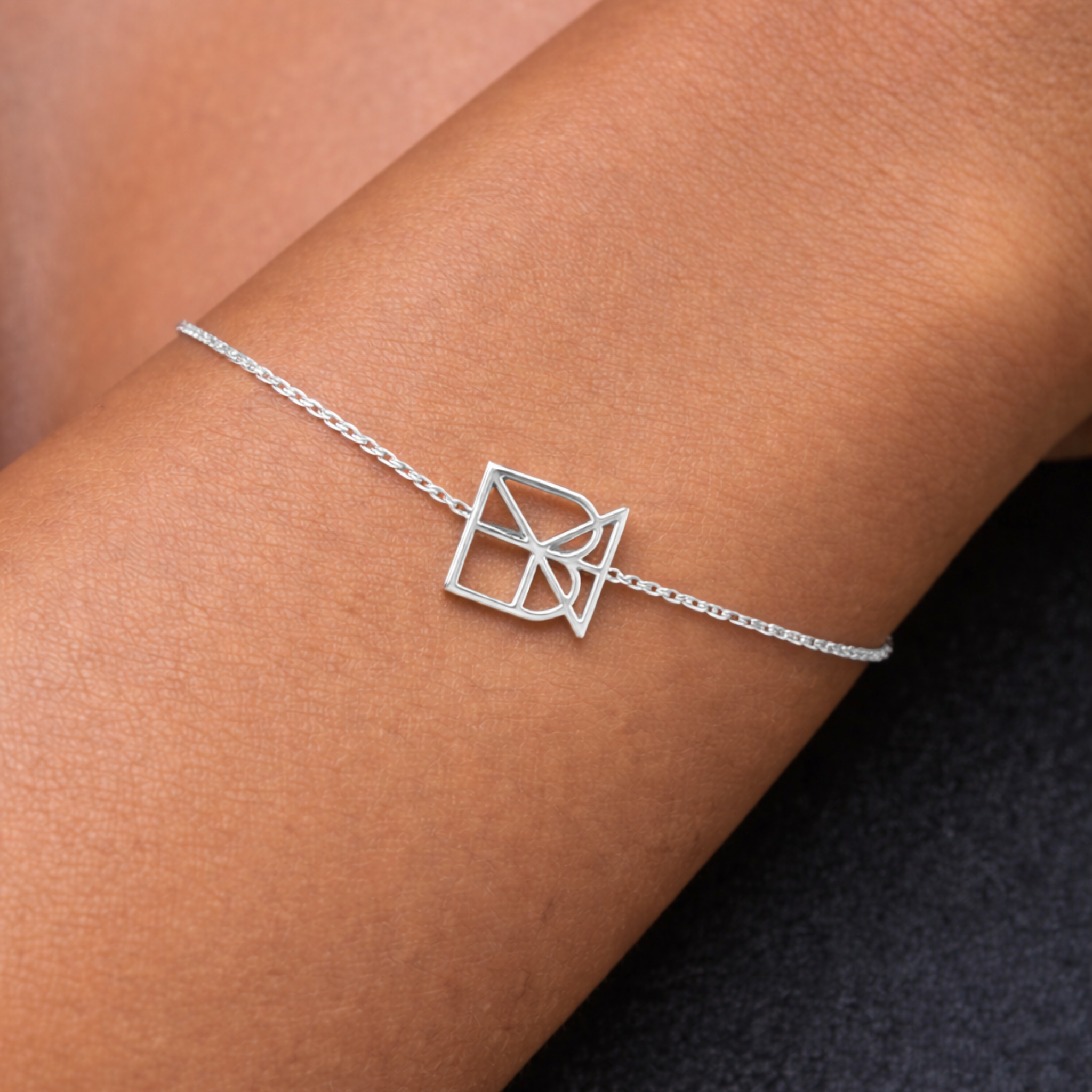 Lifestyle view of a custom 925 sterling silver geometric symbol bracelet being worn on a wrist to show scale and delicate design.