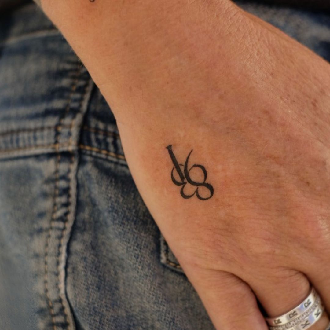 Custom 837 initial monogram tattoo on hand — fine line minimalist design by Danibydsgn.