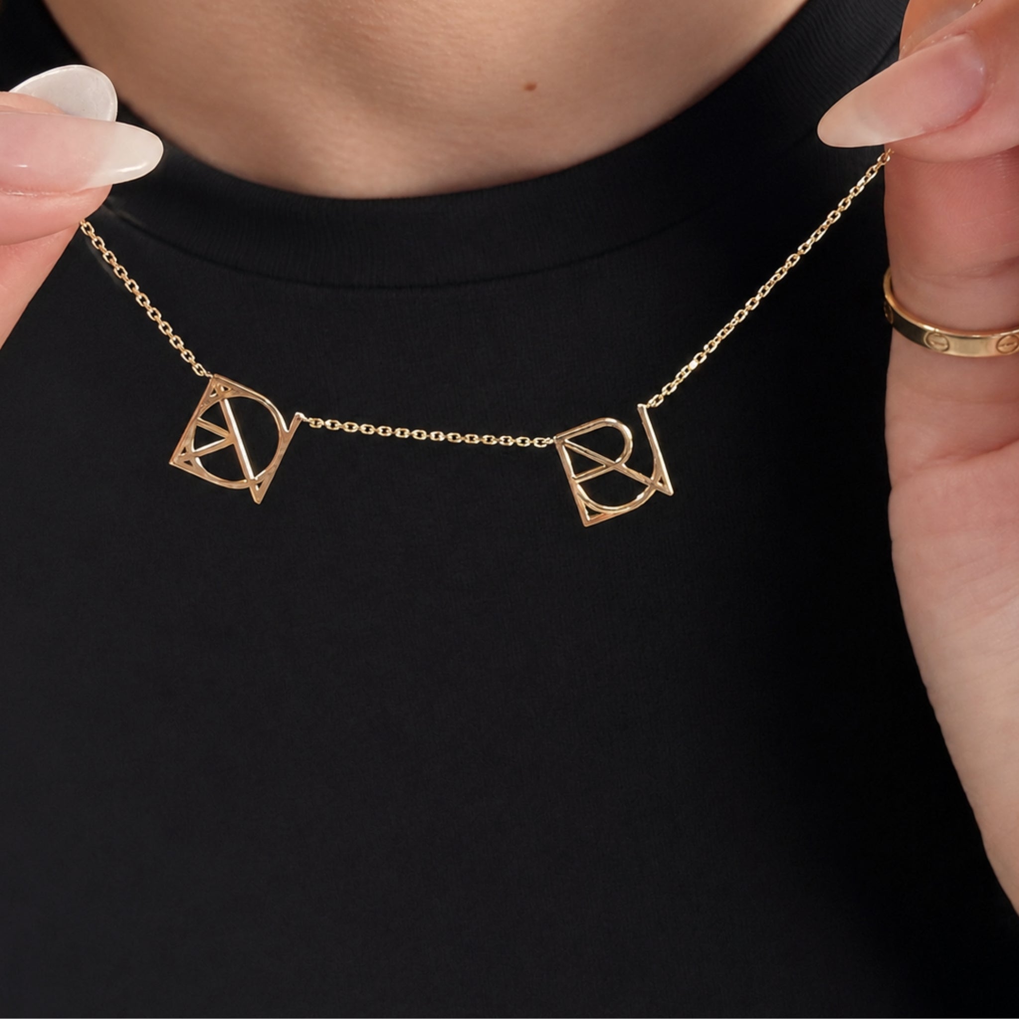 Close-up view of a Danibydsgn custom 9k gold necklace featuring two cut out jewelry symbols made to order, showcasing a minimalist jewelry style perfect for personalized gifts.