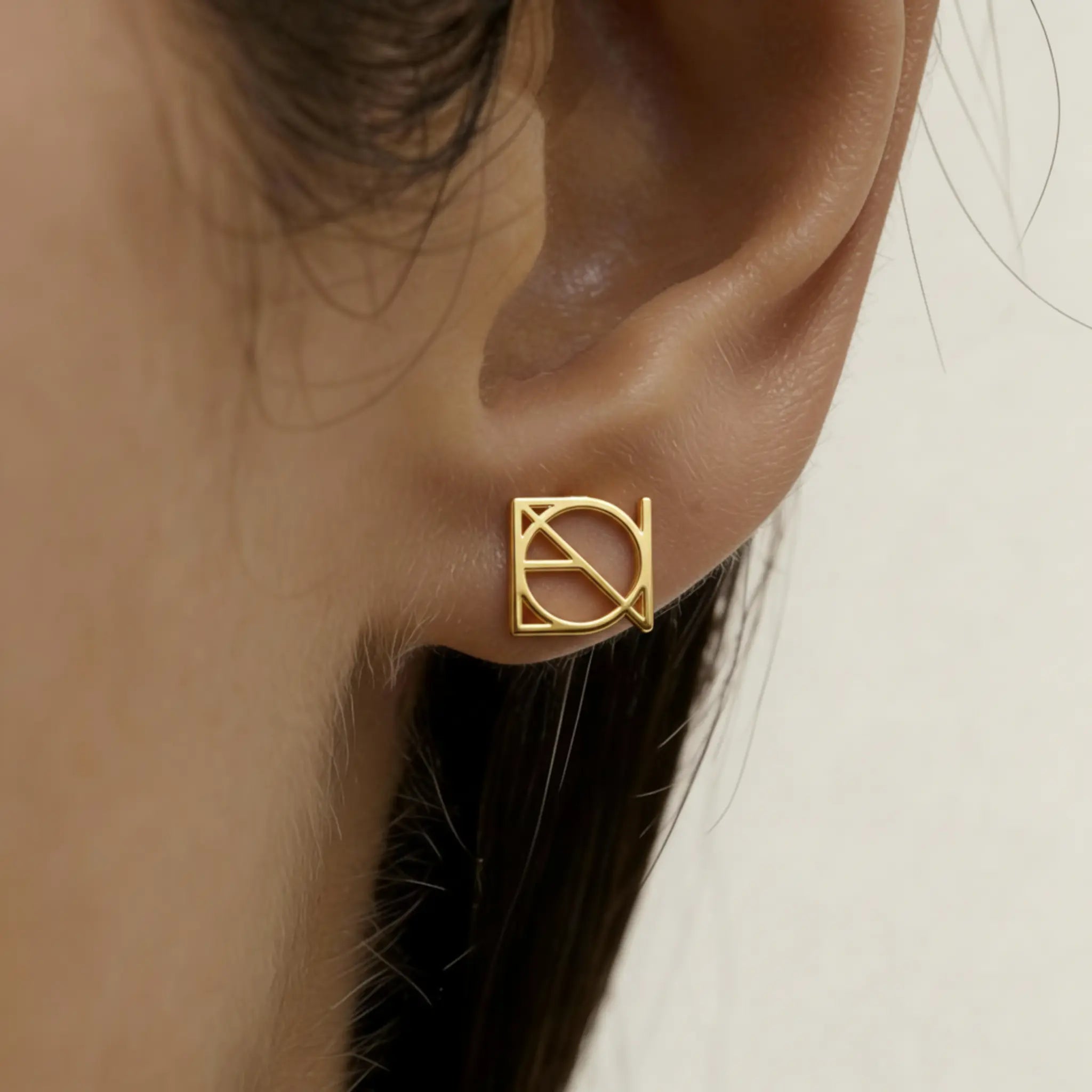 Lady is wearing gold single symbol Danibydsgn earings in 9k gold.