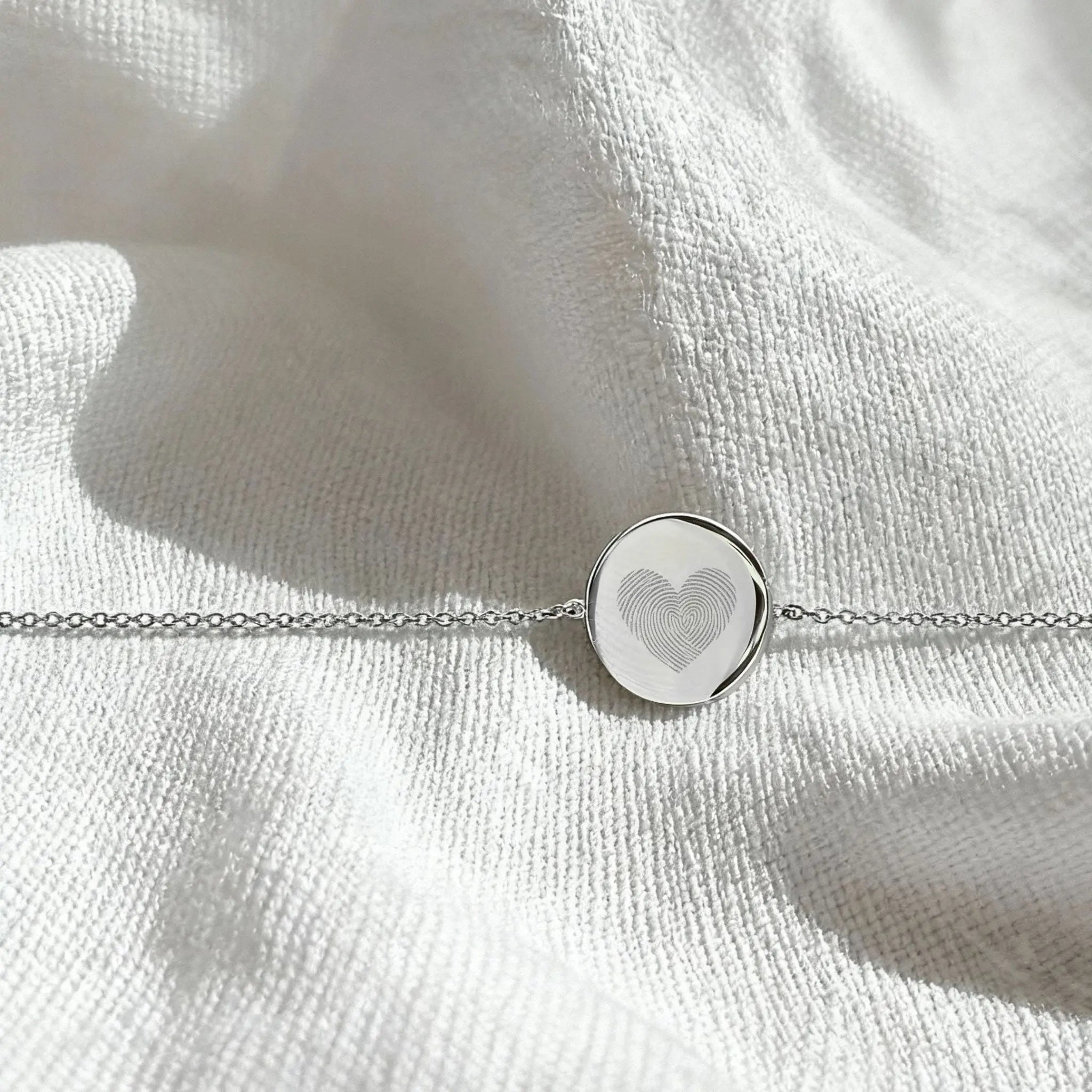Heart fingerprint coin bracelet in 925 sterling silver, elegantly displayed in natural light, showcasing its intricate design.