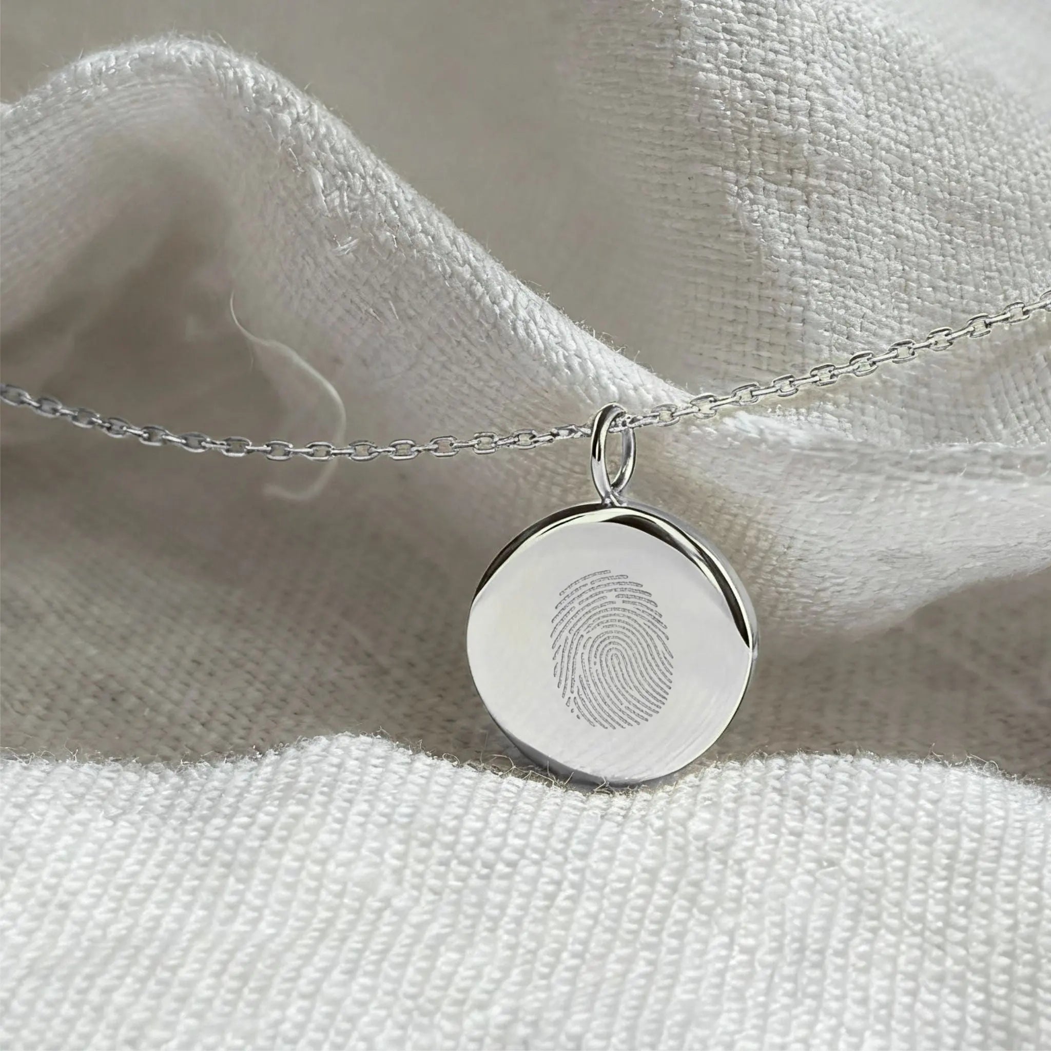 Single fingerprint coin necklace in 925 sterling silver by Danibydsgn, showcased in soft lighting.