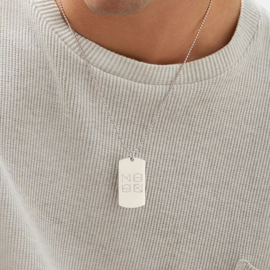 Man wearing Danibydsgn custom diamond-engraved 925 sterling silver dog tag necklace with four overlapping symbol design on adjustable bead chain