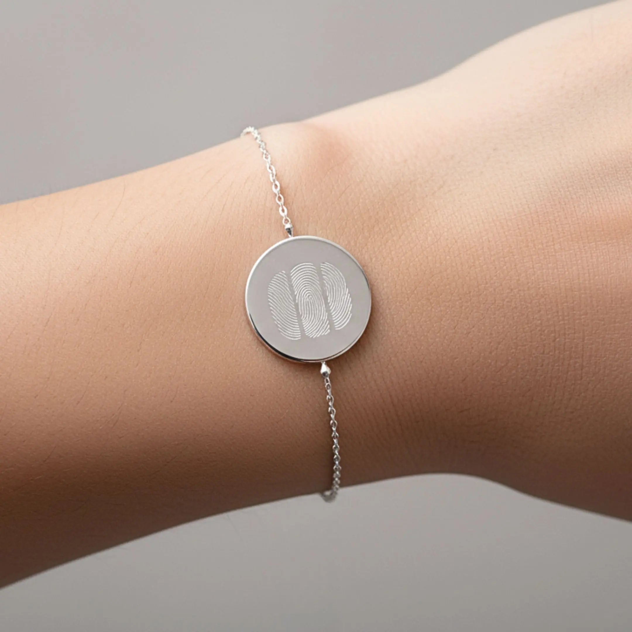 Three fingerprint coin bracelet in 925 sterling silver worn on a wrist, showcasing a delicate and personalized design.