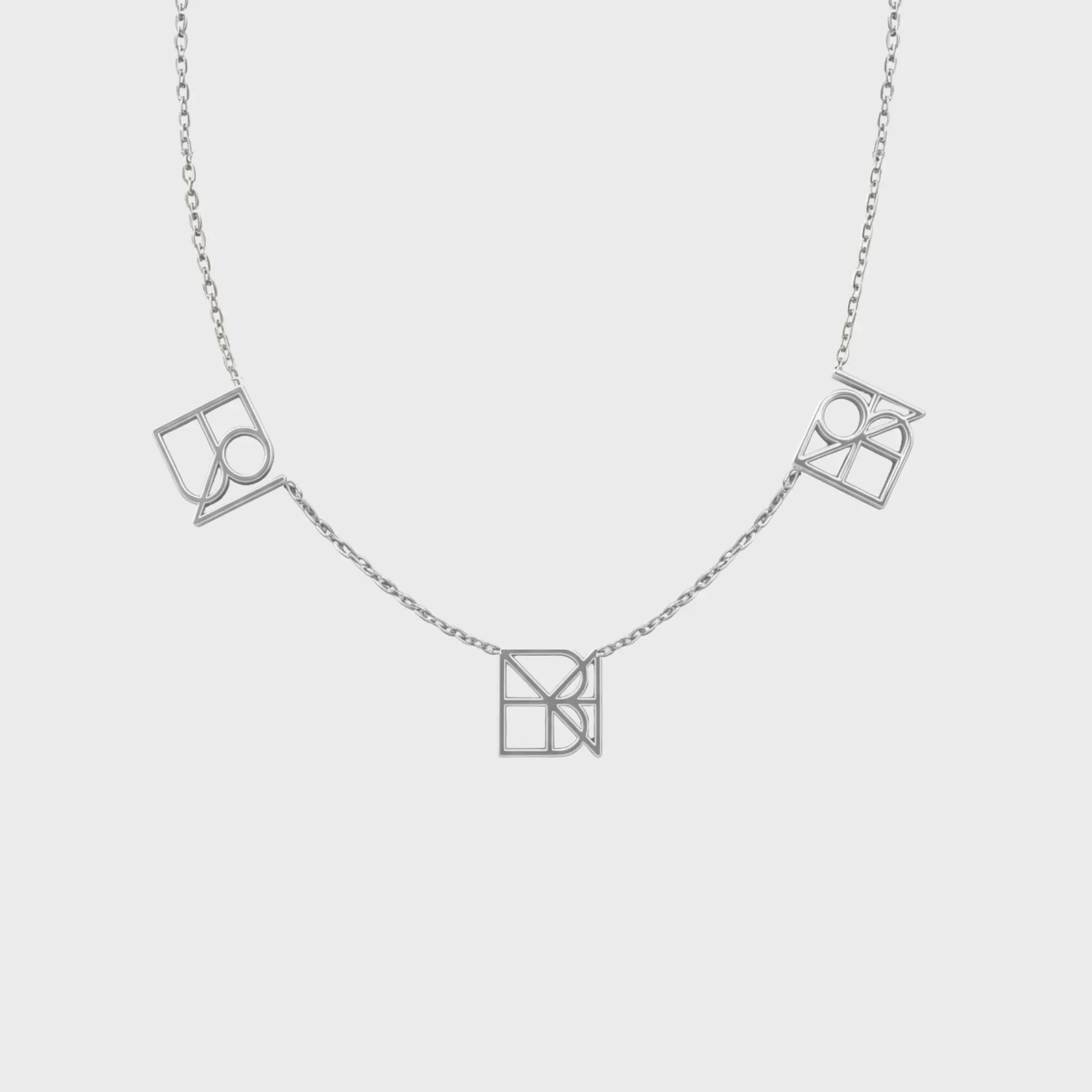 Danibydsgn three-symbol necklace in 925 sterling silver, featuring three custom cut-out symbol pendants spaced on a fine chain (front view).