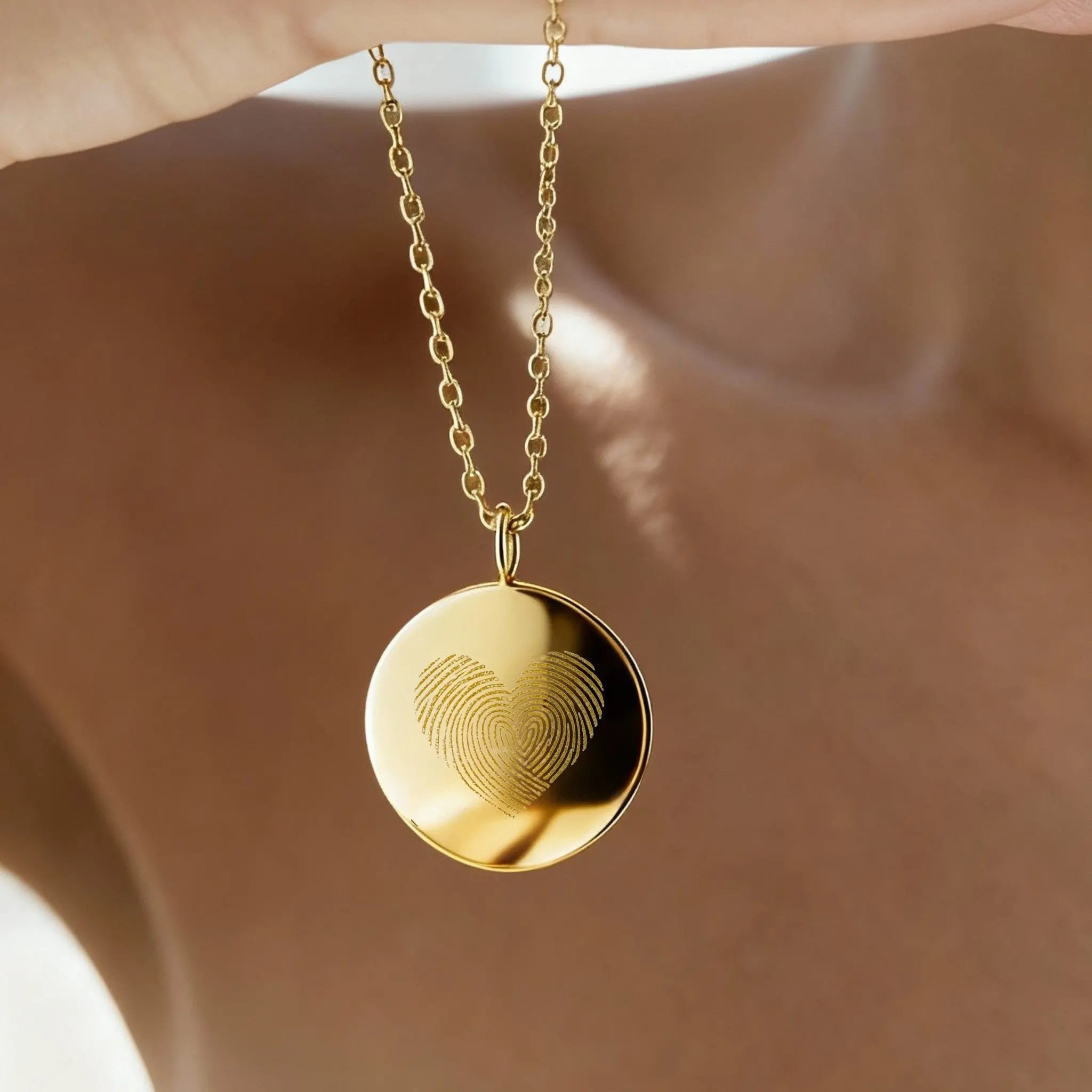 Luxury Heart Fingerprint Coin Necklace in 18K Gold Vermeil by Danibydsgn shown in natural light, featuring two overlapping fingerprints forming a heart shape. A meaningful keepsake necklace symbolising love and connection, crafted with precision engraving and a radiant gold finish for an elegant, timeless look.