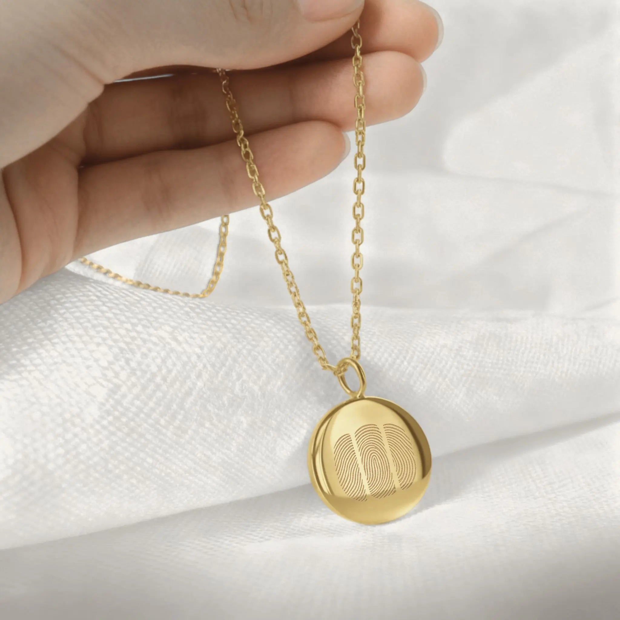 Hand holding the Luxury Three Fingerprint Coin Necklace in 18K Gold Vermeil by Danibydsgn. Features three delicately engraved fingerprints on a radiant gold pendant, symbolizing family bonds and connection. A timeless, personalized keepsake handcrafted for elegance and meaning.