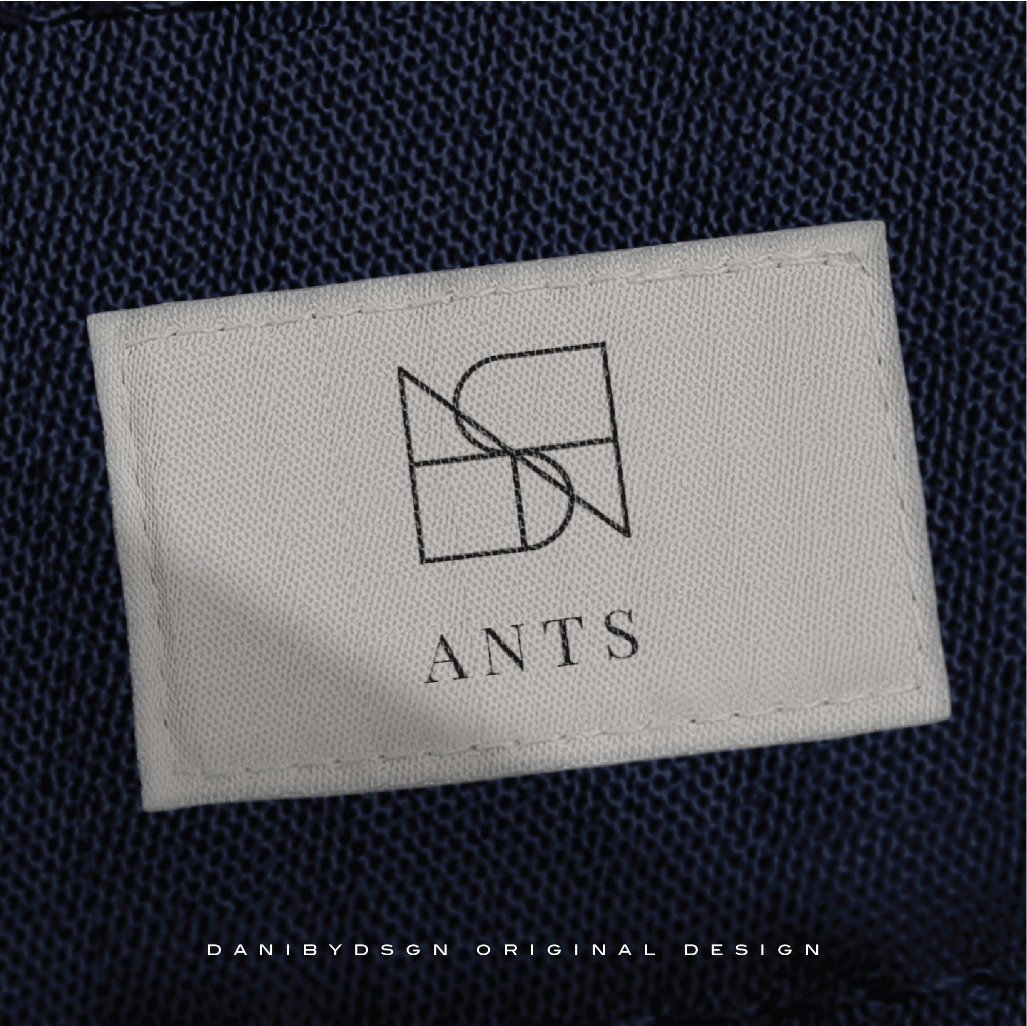 Detail of a clothing label showcasing the 'ANTS' logo with a sleek Danibydsgn Business Logo Design. The simple yet elegant logo is an example of effective small business branding, crafted by a professional graphic designer. This tag illustrates the essence of business branding through its clean logo identity, suited for website brand logos and better end clothing branding such as Tshirts and Hoodies.
