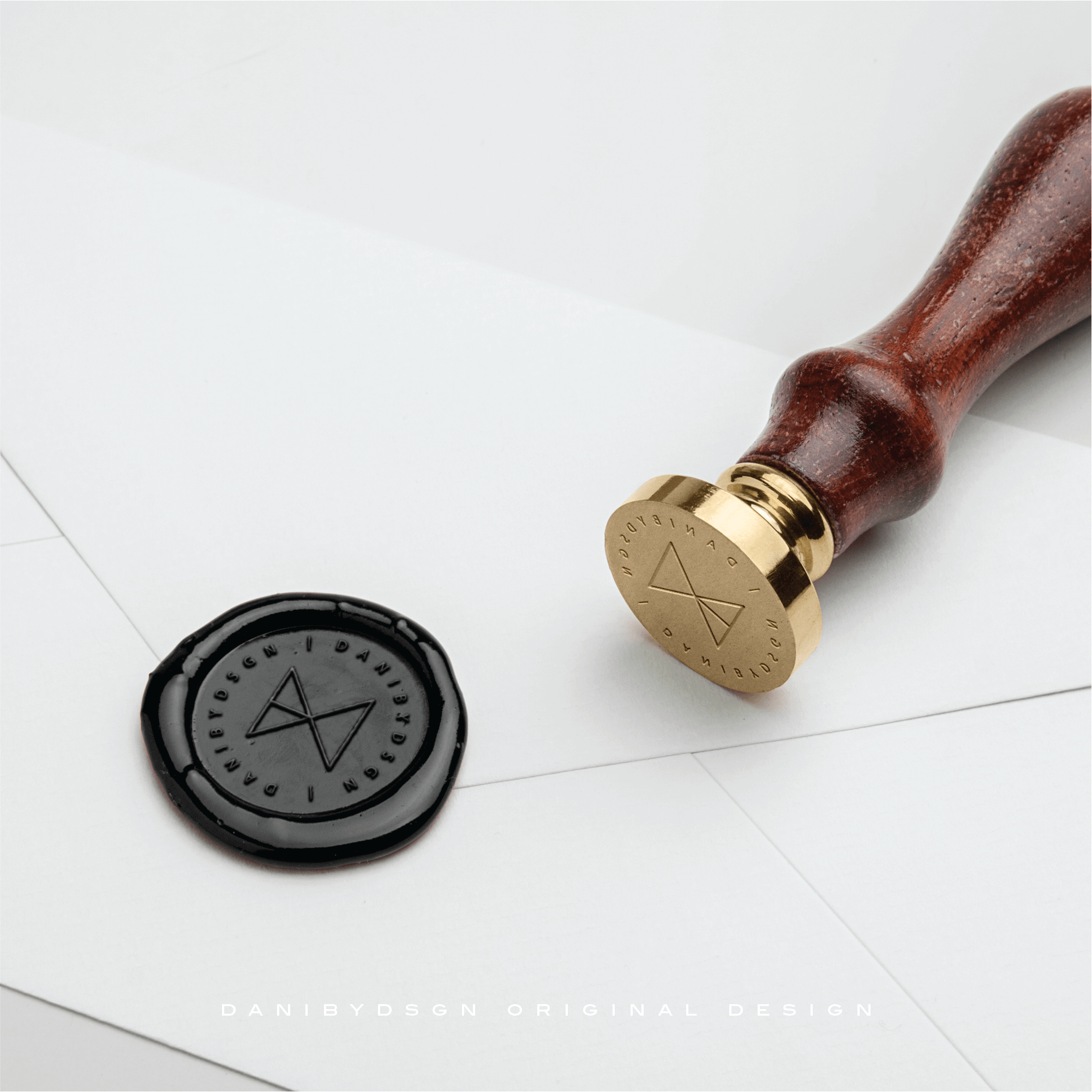 A polished Danibydsgn original Business Logo Design seal and wax impression, embodying elegance in branding. This sophisticated tool represents the merger of traditional craftsmanship and modern business branding, ideal for a company's logo identity. The seal, indicative of high-quality graphic designer work, is perfect for name logo design, adding a luxurious touch. Our logo designs are also perfect or website brand logo and clothing branding.