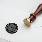 Custom business logo designed by Danibydsgn, engraved on a brass wax seal stamp and black wax imprint, showcasing how businesses use their logo branding for professional stationery and identity.