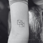 The photo is of a Joined Custom Logo used as a fineline tattoo on the arm of a lady. The design is a dynamic fusion of two or more symbols into an entwined logo joined diagonally. The designs are custom names or numbers, ideal for personal branding or as wall art or clothing branding. Custom logo design, translates into a name tattoo design and body art embodying the spirit of simple tattoo ideas while resonating with the artistry of an illustrator.
