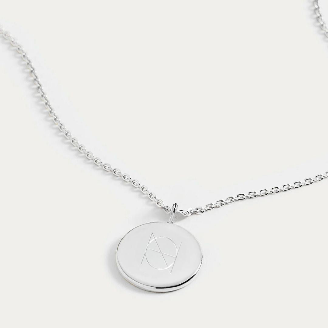 Sleek Sterling Silver Coin Necklace, featuring a single symbol Danibydsgn custom logo design engraved with precision. This elegant piece offers a personalized touch as a keepsake necklace, ideal for those who appreciate logo engraved accessories. With the option to add a name or special date, it becomes a meaningful gift that combines style and sentiment. This engraved necklace is perfect for everyday wear keepsake necklace or as a meaningful gift.  