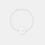 A 925 Sterling Silver coin bracelet with an engraved custom Danibydsgn logo design on it, of one symbol on a light coloured background.