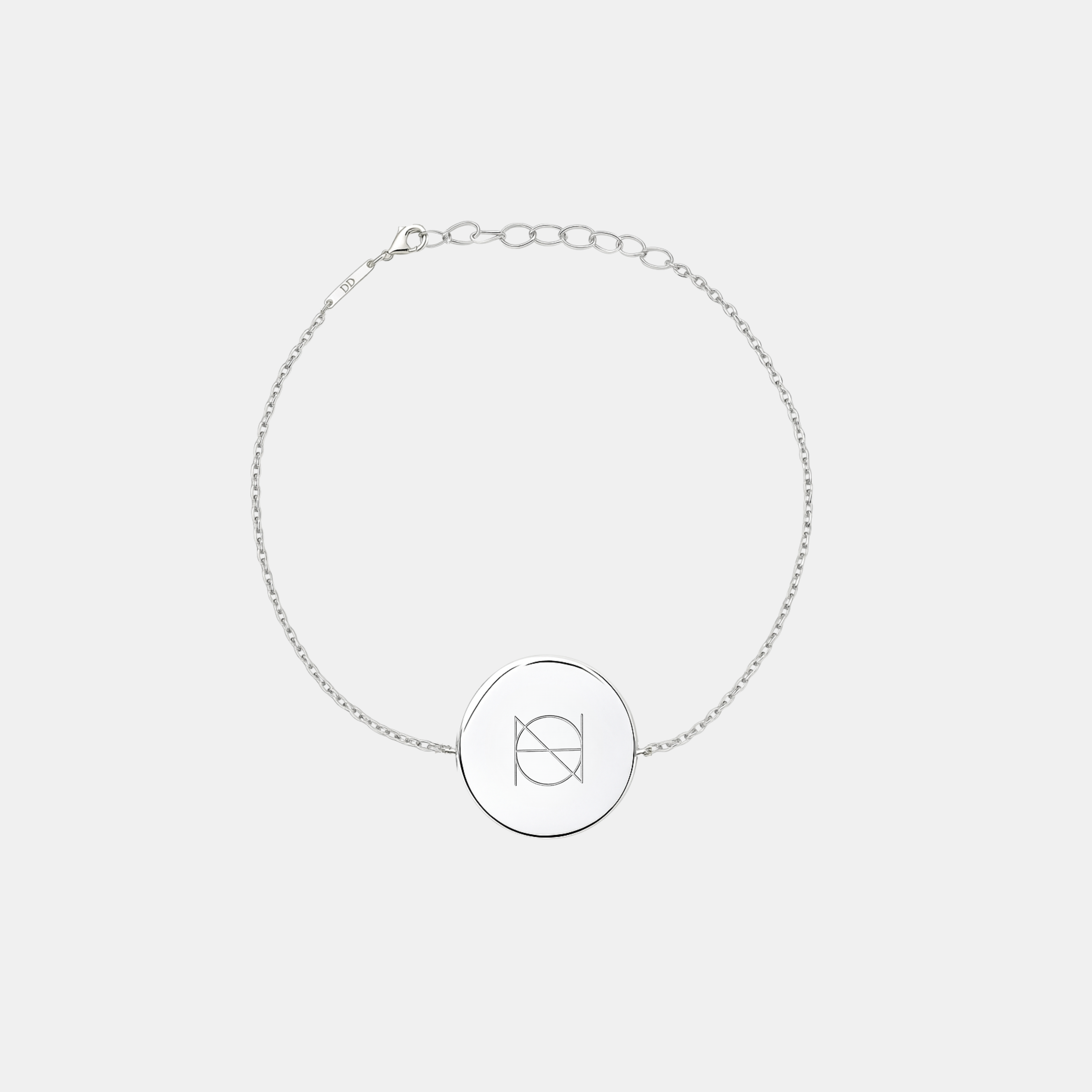 A 925 Sterling Silver coin bracelet with an engraved custom Danibydsgn logo design on it, of one symbol on a light coloured background.