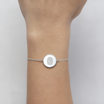 925 Sterling Silver bracelet with a circular coin pendant design engraved with one fingerprints, on a lady's wrist against a neutral background