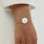 925 Sterling Silver bracelet with a circular pendant featuring a custom Danibydsgn single symbol design and bracelet is on a lady's wrist.
