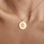 18k Gold Vermeil luxury coin pendant necklace with a single fingerprint engraved on the pendant and pendant is around the neck of a lady.  Close up photo.