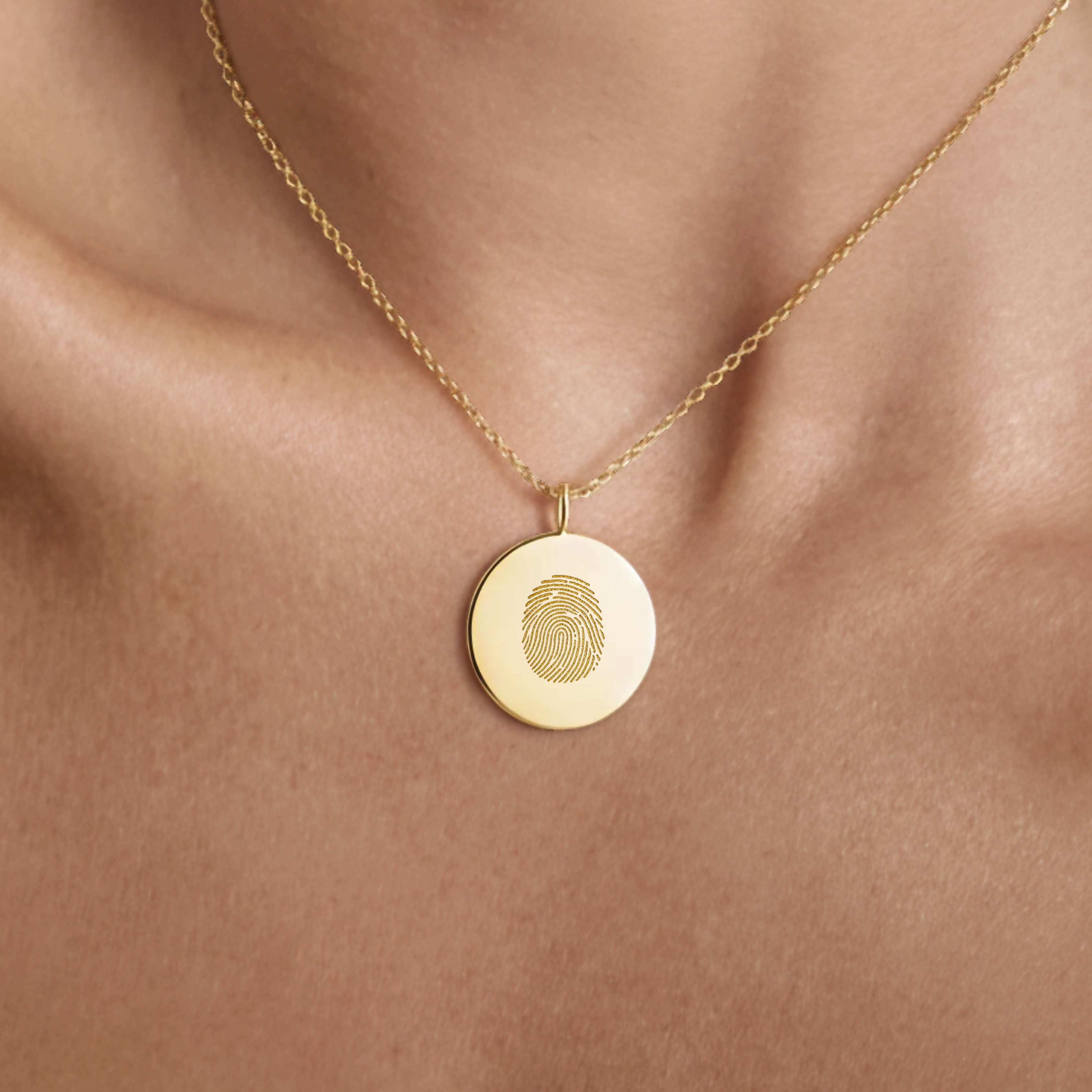 18k Gold Vermeil luxury coin pendant necklace with a single fingerprint engraved on the pendant and pendant is around the neck of a lady.  Close up photo.