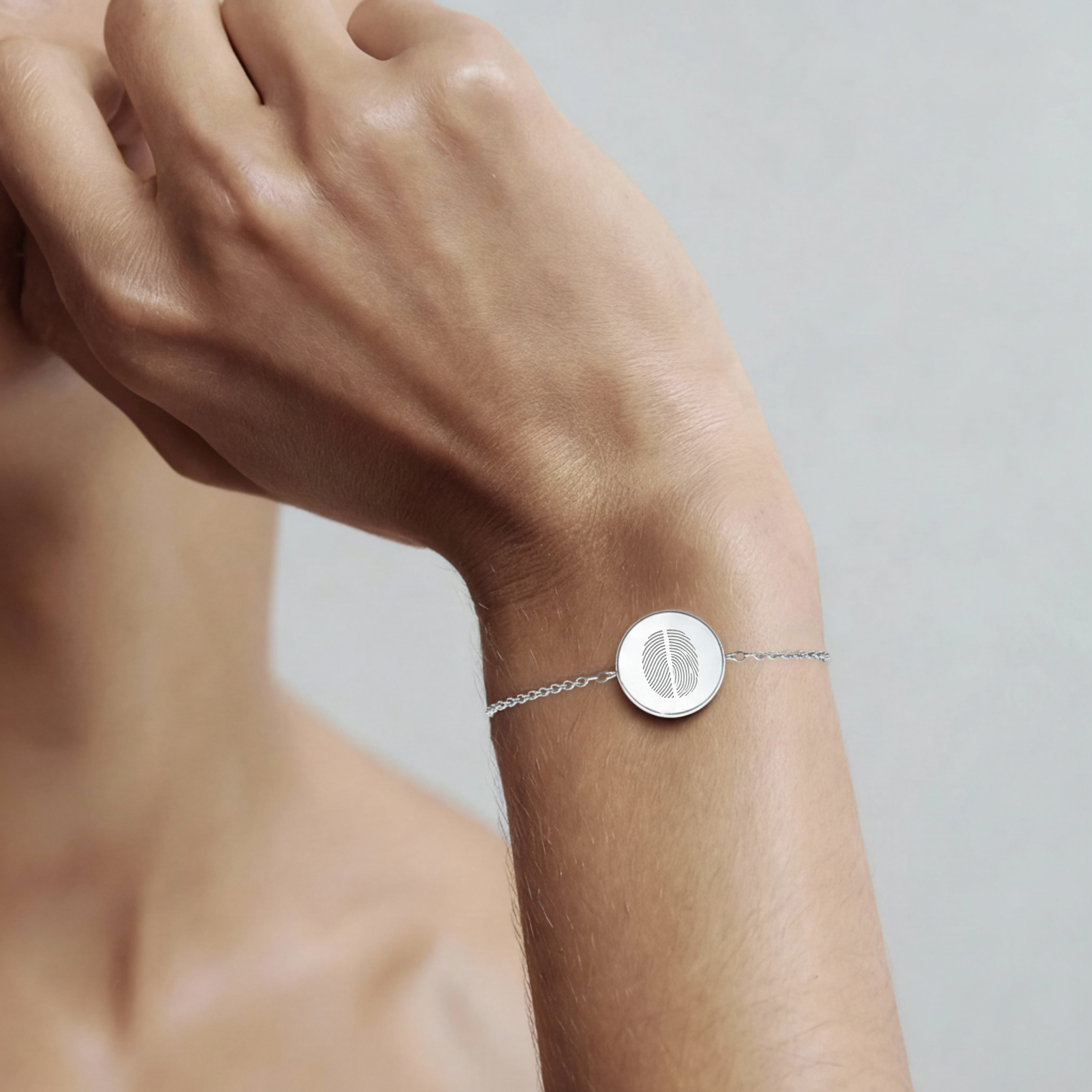 925 Sterling Silver bracelet with a circular coin pendant design engraved with two fingerprints, on a lady's wrist against a neutral background