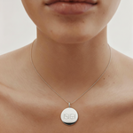 Close-up of a lady wearing our luxury coin pendant necklace in 925 sterling silver necklace around her neck.  Pendant is engraved with two Danibydsgn custom symbols.