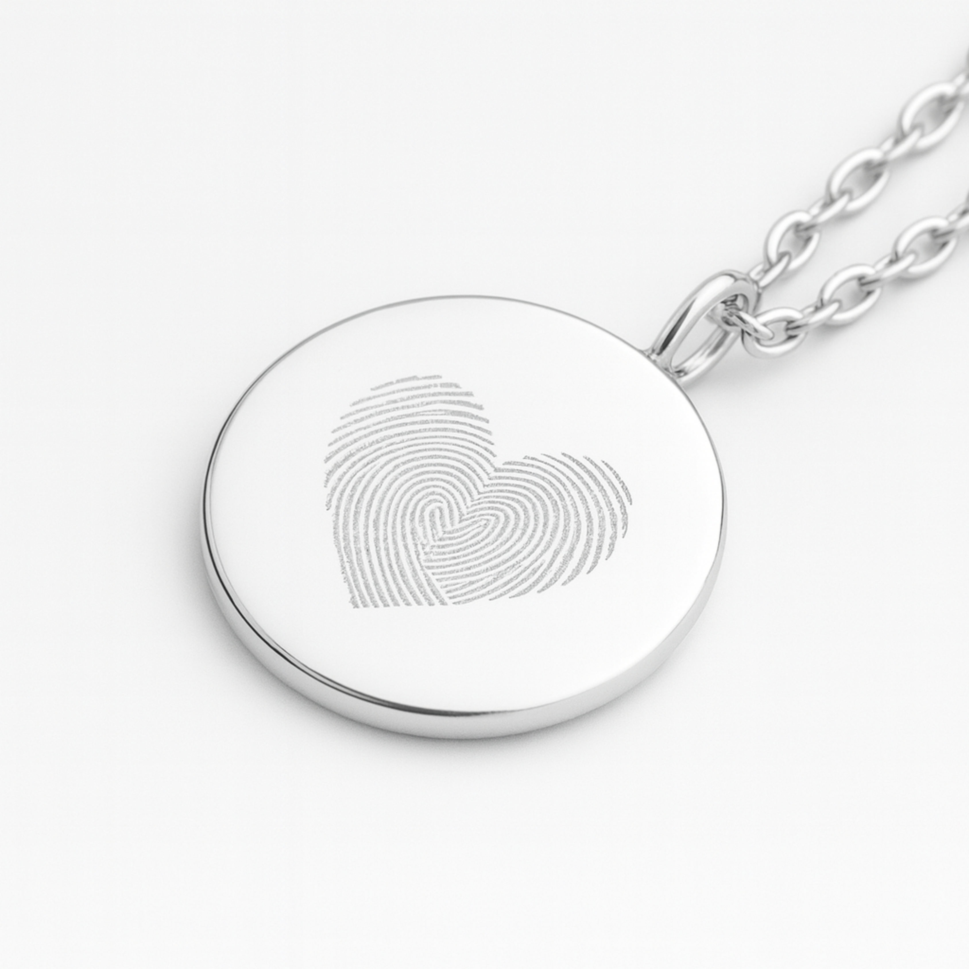 925 sterling silver  luxury coin pendant necklace with heart fingerprints engraved on the pendant and pendant is on a chain on a light coloured background
