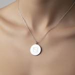 Close-up of a lady wearing our luxury coin pendant necklace in 925 sterling silver necklace around her neck.  Pendant is engraved with one Danibydsgn custom symbols.