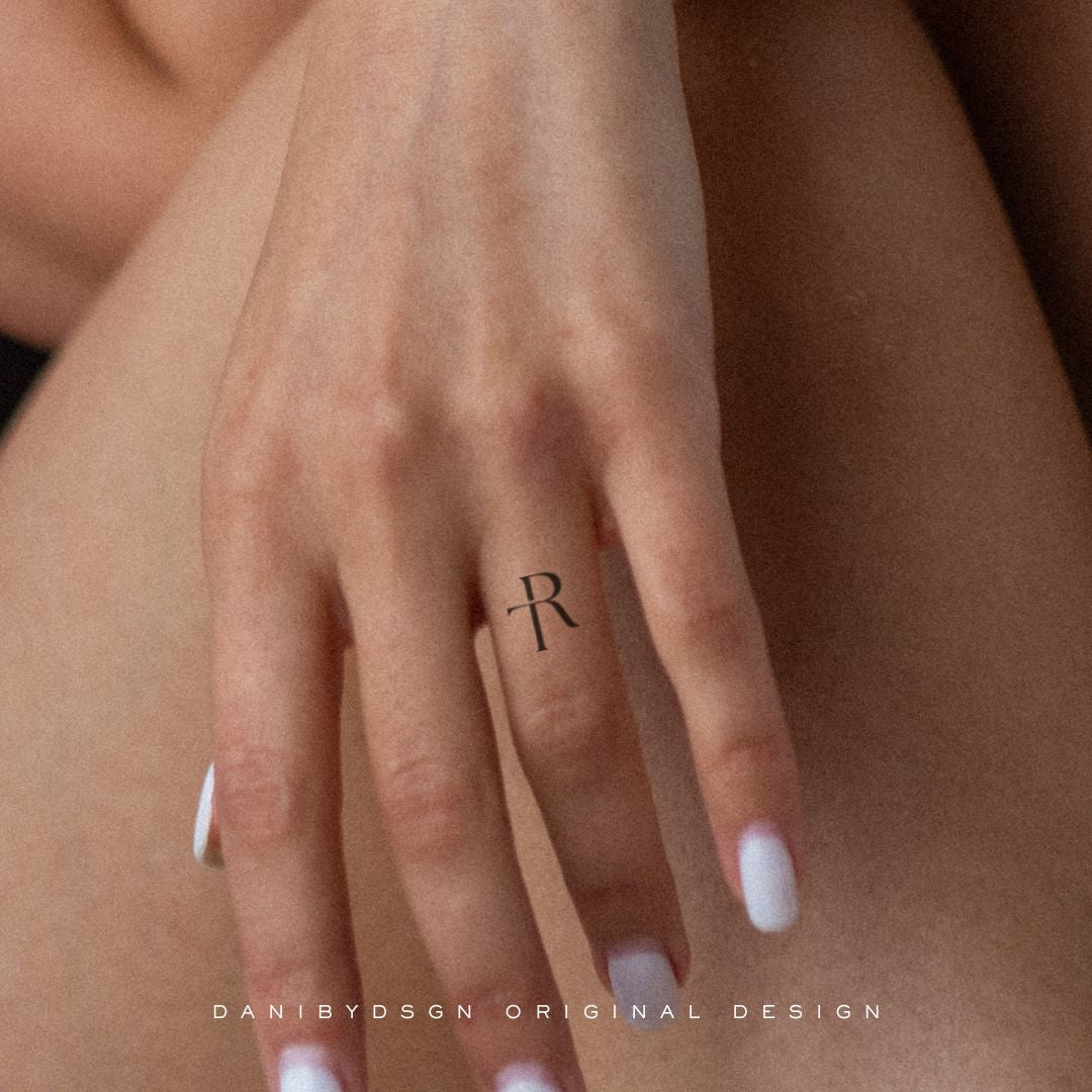 Close-up of a delicate 'TR' initial monogram tattoo on a hand, exemplifying Danibydsgn's custom logo design tailored for personal branding, body art and tattoo design. This minimalist name monogram serves as a subtle expression of identity, blending and personal branding.   The artful domains of tattoo design, business logo designs, and personal branding. Danibydsgn initial monograms are perfect for wedding monograms, wall art, clothing branding and special event marketing.  