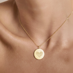 18k Gold Vermeil luxury coin pendant necklace with 2 fingerprints  in a heart shape engraved on the pendant and pendant is around the neck of a lady.