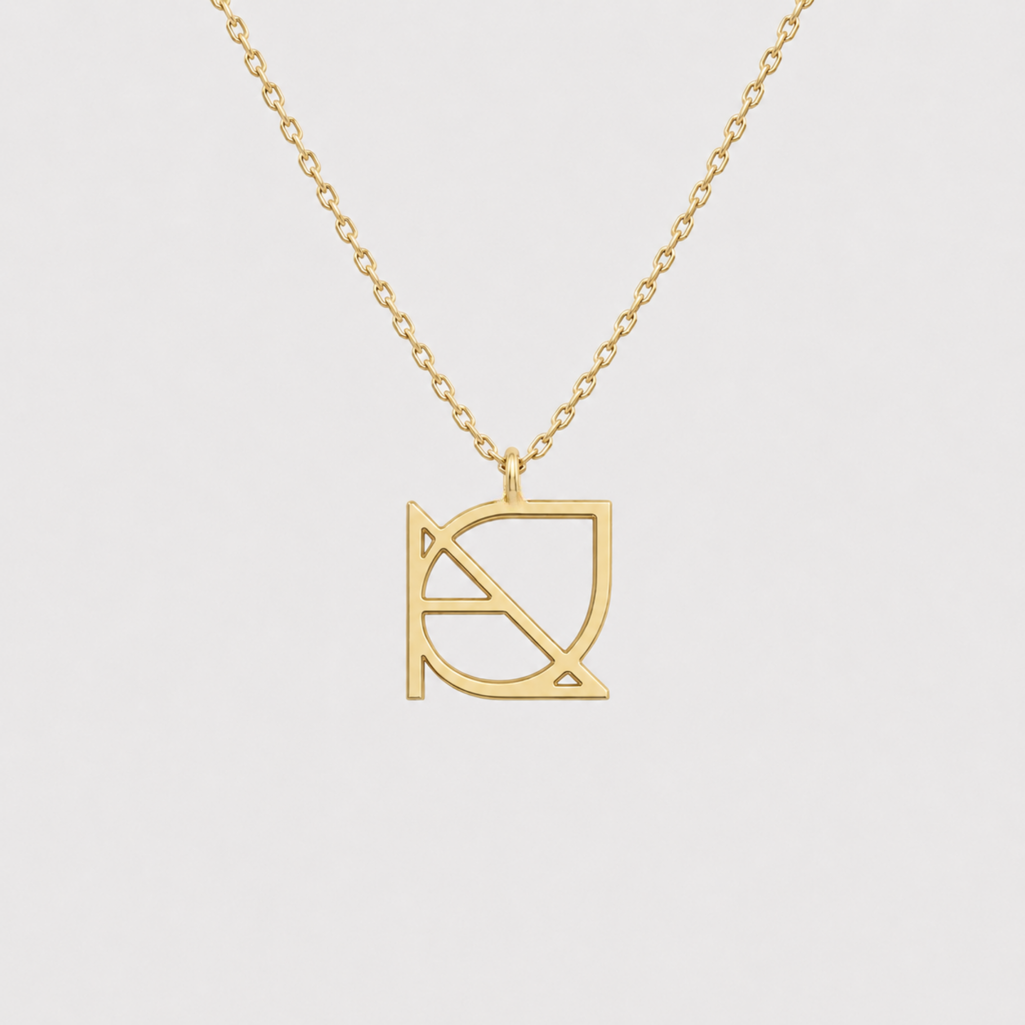 A studio shot of a custom necklace in 9k gold against a white background, highlighting a minimalist jewelry piece featuring a unique hand-designed Danibydsgn symbol cut out jewelry pendant hanging from a top jump ring attachment.