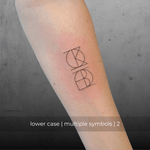 A minimalistic fine line tattoo of an overlapping Custom Logos design on a person's inner arm of a two symbol design in lowercase letters, exemplifying custom logo design, name tattoo design, and body art. This simple small  tattoo idea showcases personal branding and tattoo art, ideal for both name logos and wall art applications.