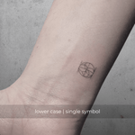 A minimalistic fineline tattoo of an overlapping Custom Logos design on a person's wrist of a single symbol design in lowercase letters, exemplifying custom logo design, name tattoo design, and body art. This simple small tattoo idea showcases personal branding and tattoo art, ideal for both name logos and wall art applications.