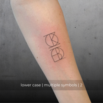 A minimalistic fine line tattoo of an overlapping logo design on a person's inner arm of a two symbol design in lowercase letters, exemplifying custom logo design, name tattoo design, and body art. This simple tattoo idea showcases personal branding and tattoo art, ideal for both name logos and wall art applications.