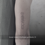 A minimalistic fine line tattoo of an overlapping logo design on a person's outer arm of a five symbol design in lowercase letters, exemplifying custom logo design, name tattoo design, and body art. This simple tattoo idea showcases personal branding and tattoo art, ideal for both name logos and wall art applications.