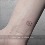 A minimalistic fineline tattoo of an overlapping Custom Logos design on a person's wrist of a single symbol design in lowercase letters, exemplifying custom logo design, name tattoo design, and body art. This simple tattoo idea showcases personal branding and tattoo art, ideal for both name logos and wall art applications.