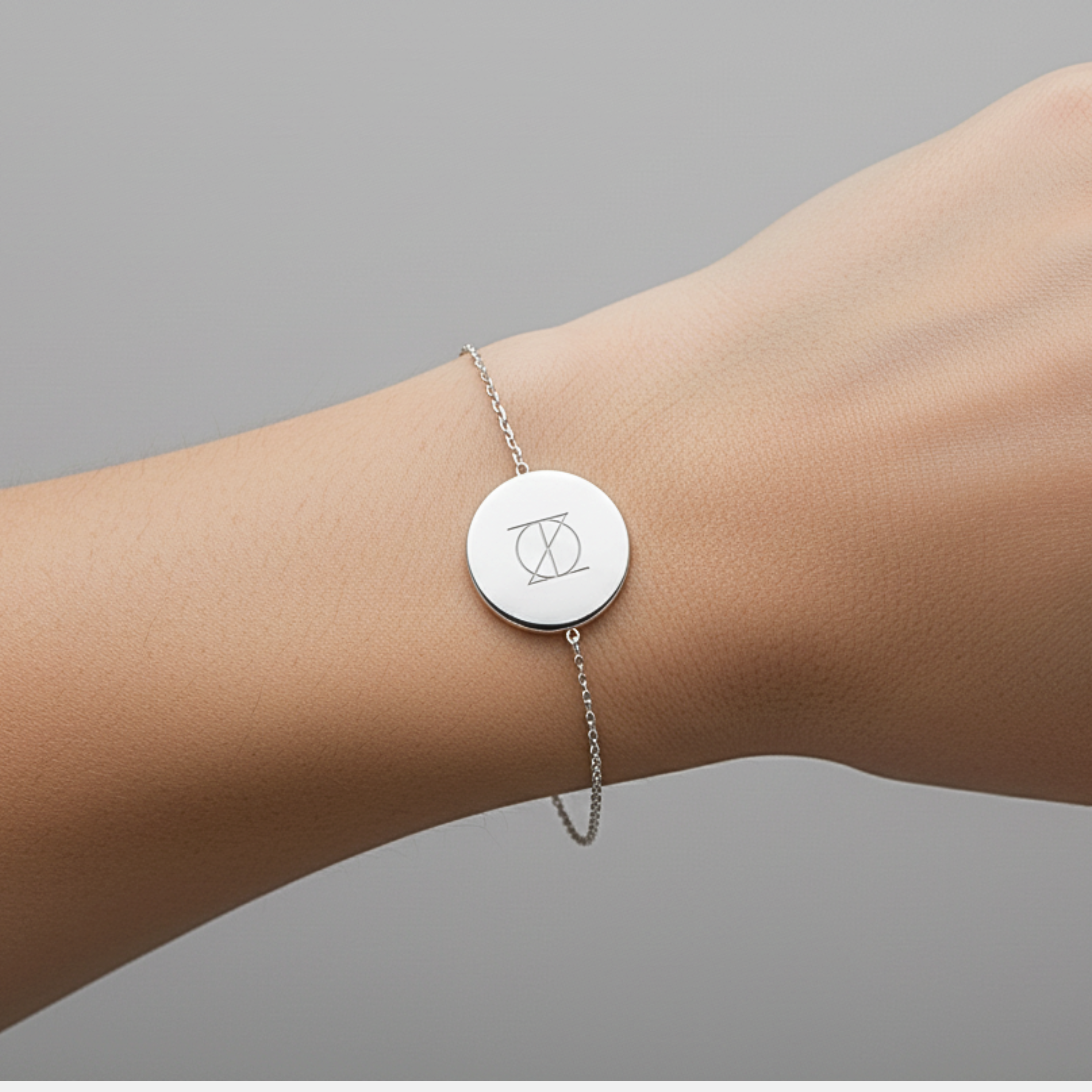 925 Sterling Silver bracelet with a circular pendant featuring a custom Danibydsgn single symbol design and bracelet is on a lady's wrist.