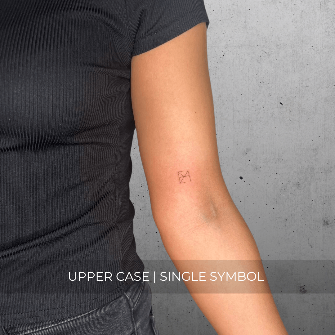 A minimalistic fineline tattoo of an overlapping Custom Logos design on a person's inner arm of a single symbol design in uppercase letters, exemplifying custom logo design, name tattoo design, and body art. This simple tattoo idea showcases personal branding and tattoo art, ideal for both name logos and wall art applications.