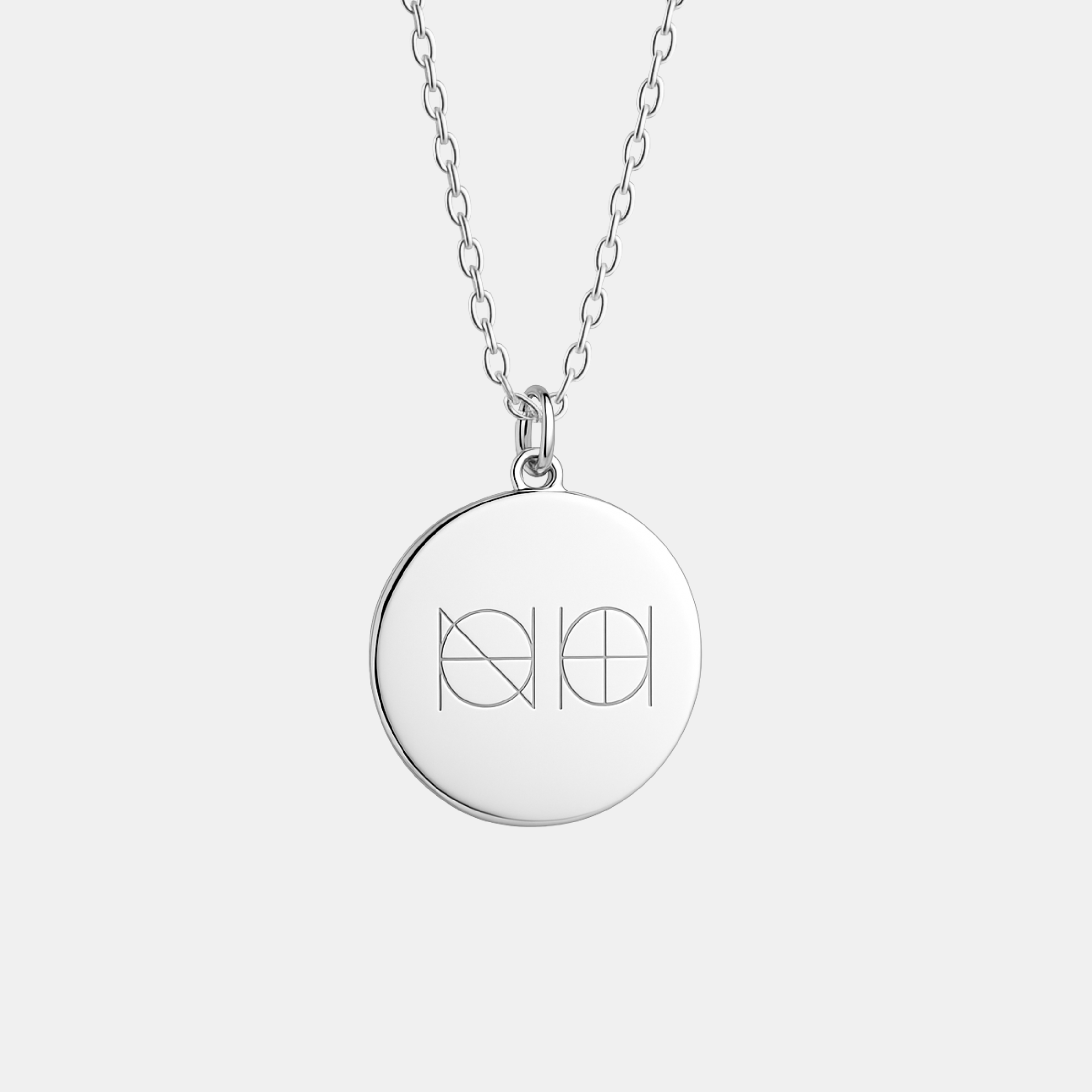 Close-up of the Danibydsgn custom engraved coin necklace in 925 sterling silver, featuring a two-symbol geometric logo engraving on a smooth polished round pendant suspended from a fine silver chain against a neutral background.