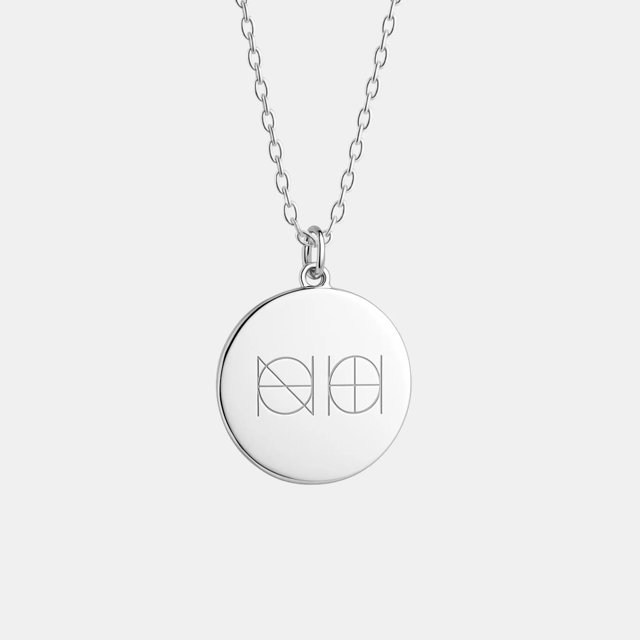 Close-up of Danibydsgn engraved pendant necklace in 925 sterling silver featuring two symbols on a coin design.