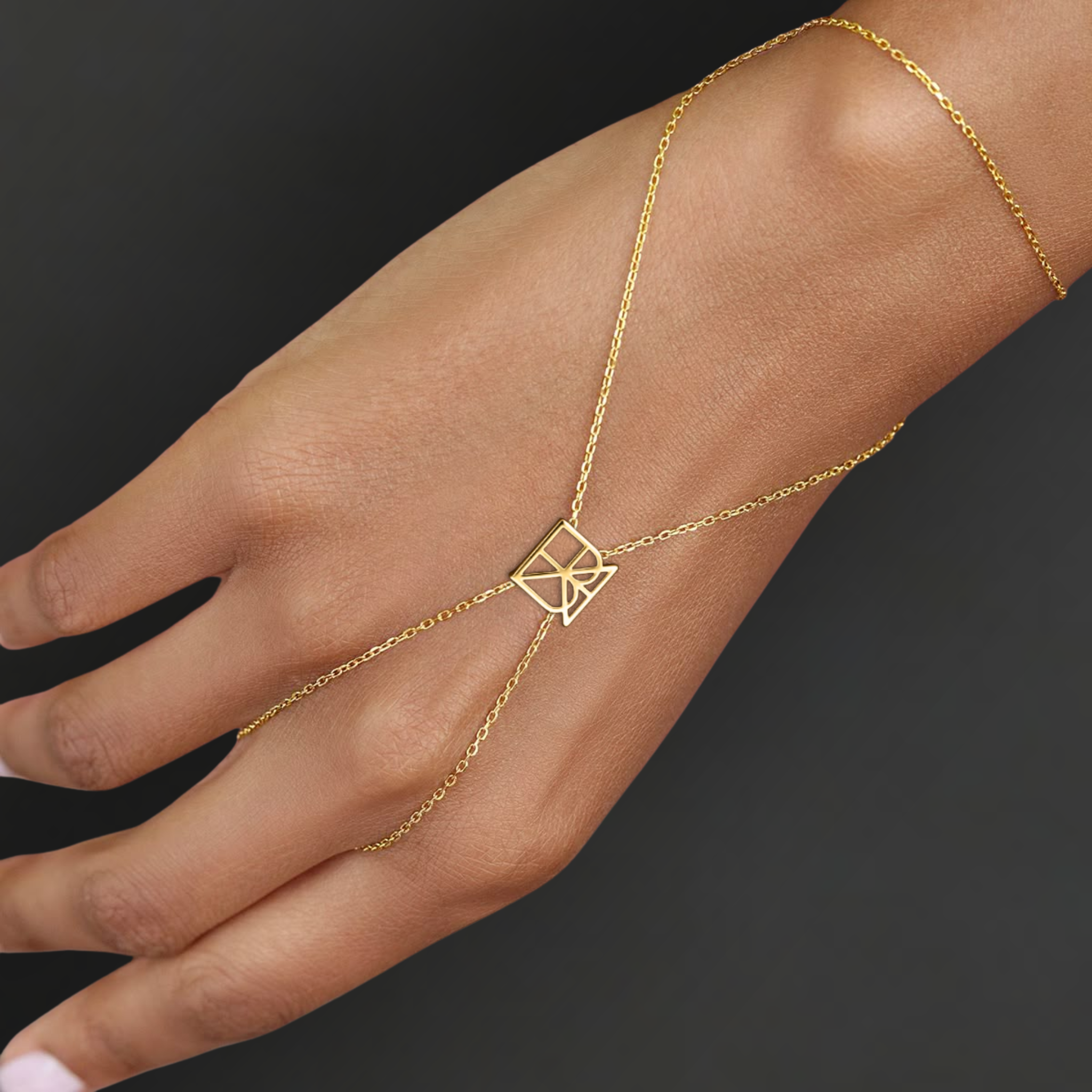 Danibydsgn custom symbol hand chain in 9K gold worn on hand, showing the fine chain drape and geometric cut-out symbol connector.