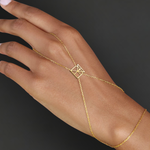 Model wearing Danibydsgn custom symbol hand chain in 9K gold, with a geometric cut-out symbol connector across the back of the hand.