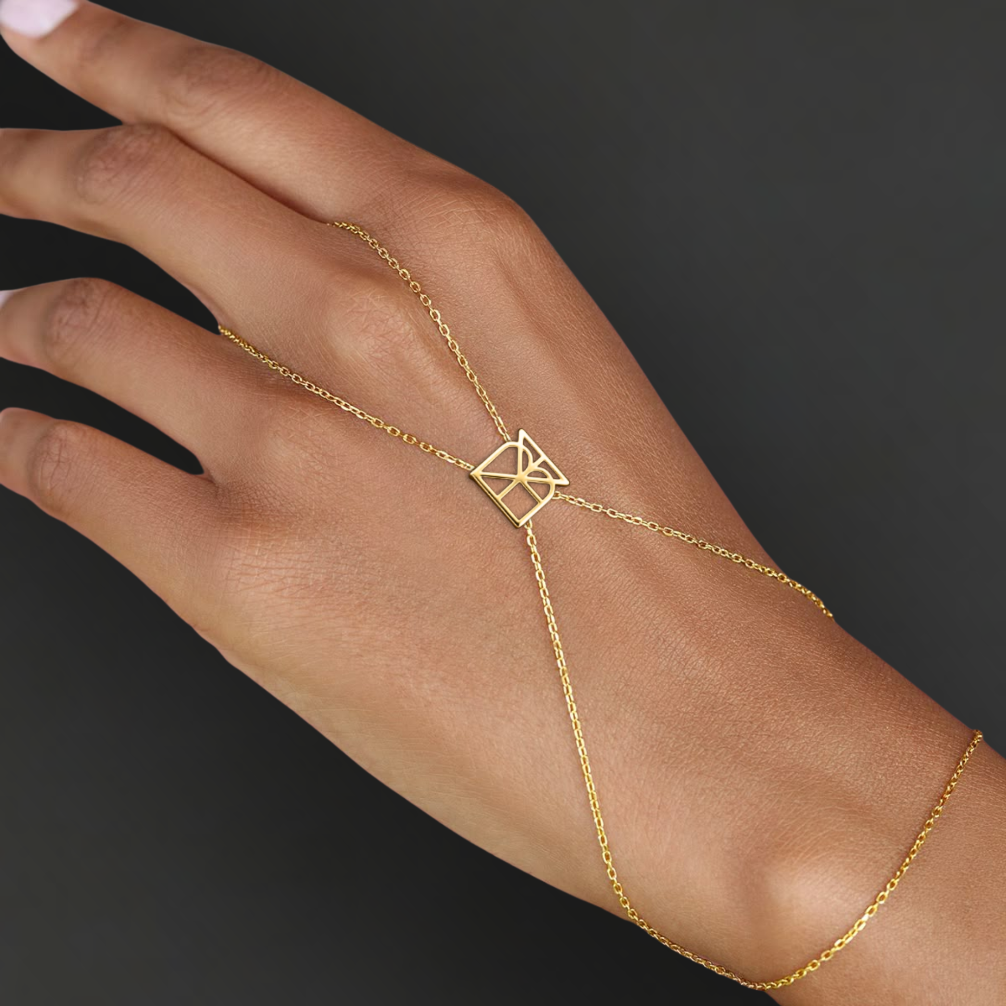 Model wearing Danibydsgn custom symbol hand chain in 9K gold, with a geometric cut-out symbol connector across the back of the hand.