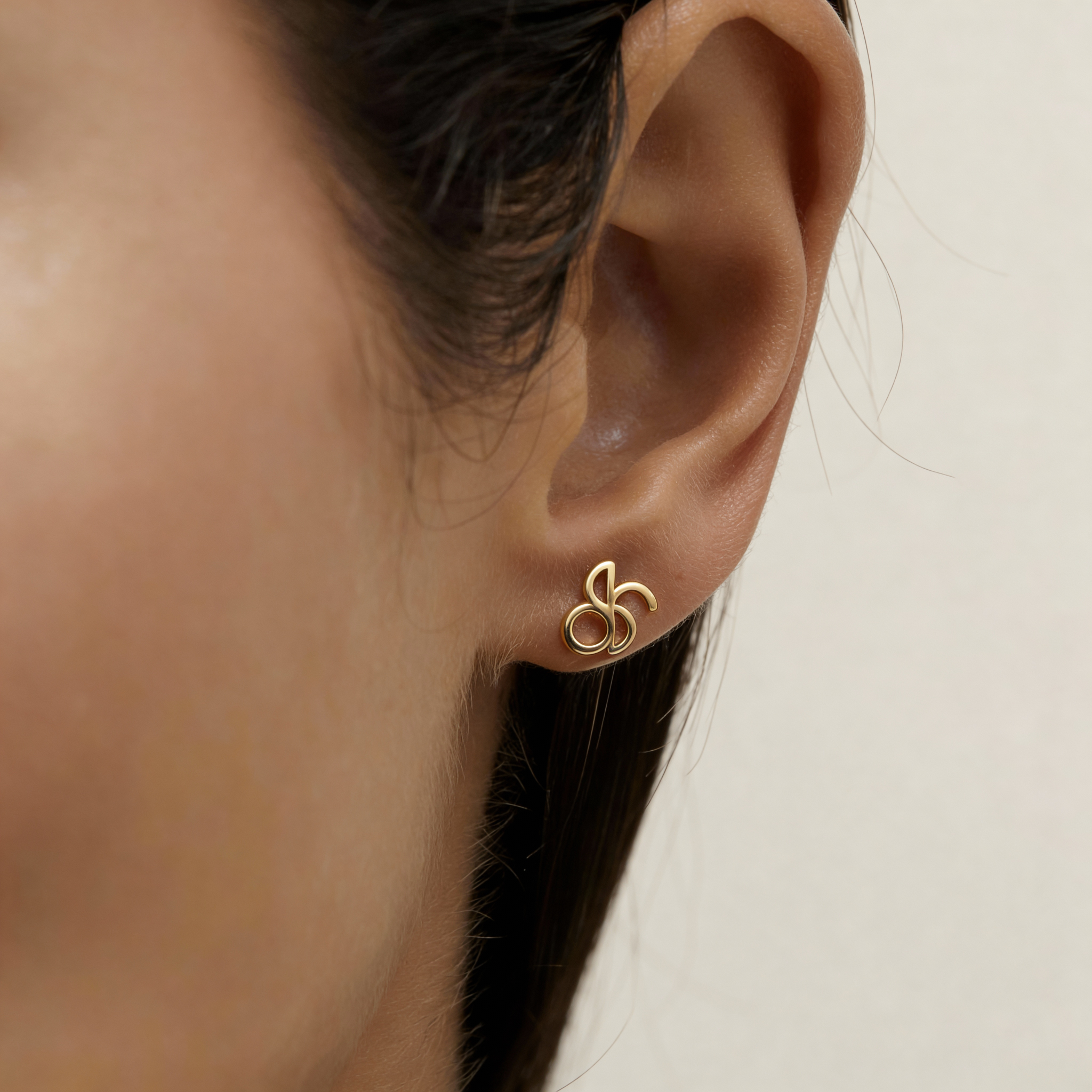 Danibydsgn custom symbol stud earring in 9k Gold worn on ear, featuring a cut-out silhouette design.