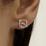 Danibydsgn custom symbol stud earring in 925 sterling silver worn on ear by a lady,  featuring a cut-out silhouette of the design in uppercase letters.