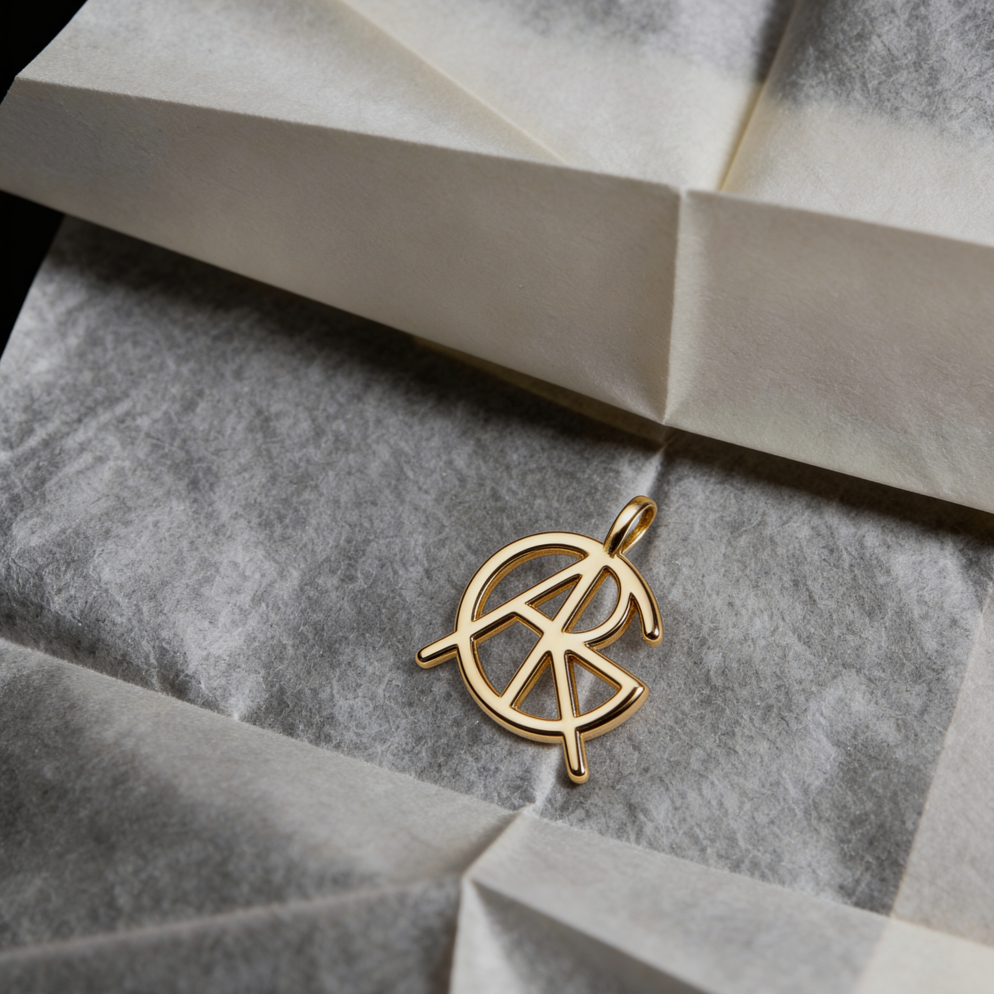 A standalone custom necklace charm option without the chain, showcasing a meaningful jewelry piece featuring a single hand-designed Danibydsgn symbol cut out jewelry pendant in 9k gold resting on textured paper packaging.