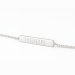 Side view of the Danibydsgn engravable bar bracelet in polished 925 sterling silver, showcasing a precise four-symbol geometric logo engraving on a slim rectangular bar with fine linked chain detail.
