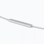 Angled close-up of the Danibydsgn engravable bar bracelet in 925 sterling silver, showing the slim rectangular plate engraved with a three-symbol geometric logo and attached to a fine silver chain.