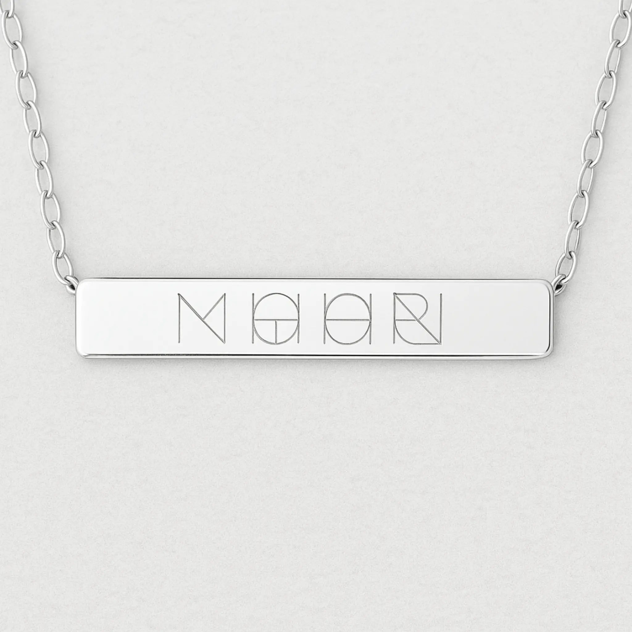 Close-up of Danibydsgn engraved bar necklace in 925 sterling silver featuring a unique four-symbol design.