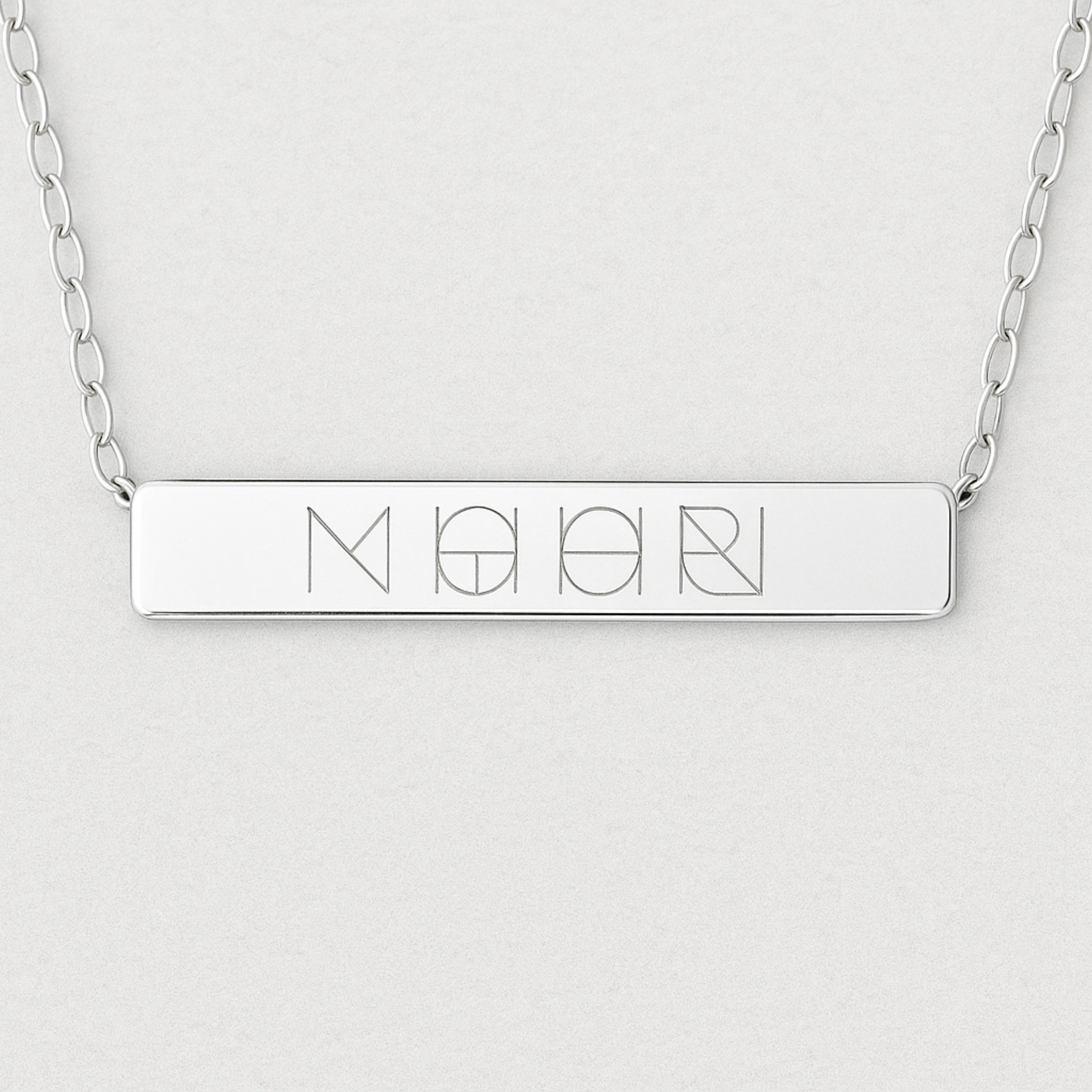 Close-up of the Danibydsgn engraved bar necklace in 925 sterling silver, showcasing the polished rectangular pendant with a detailed four-symbol geometric engraving and fine silver chain links on each side.